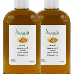 May include: Two clear glass bottles of toasted sesame oil, each containing 12 fluid ounces (355 ml). The bottles have white labels with the brand name "Soapeauty" and the words "toasted sesame oil" printed in black. The labels also include the ingredients, "Sesame Oil (Sesamum Indicum)", and instructions to store in a cool, dry place.