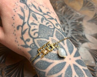 May include: Gold chain bracelet with a charm that says "555" and a white pearl pendant.