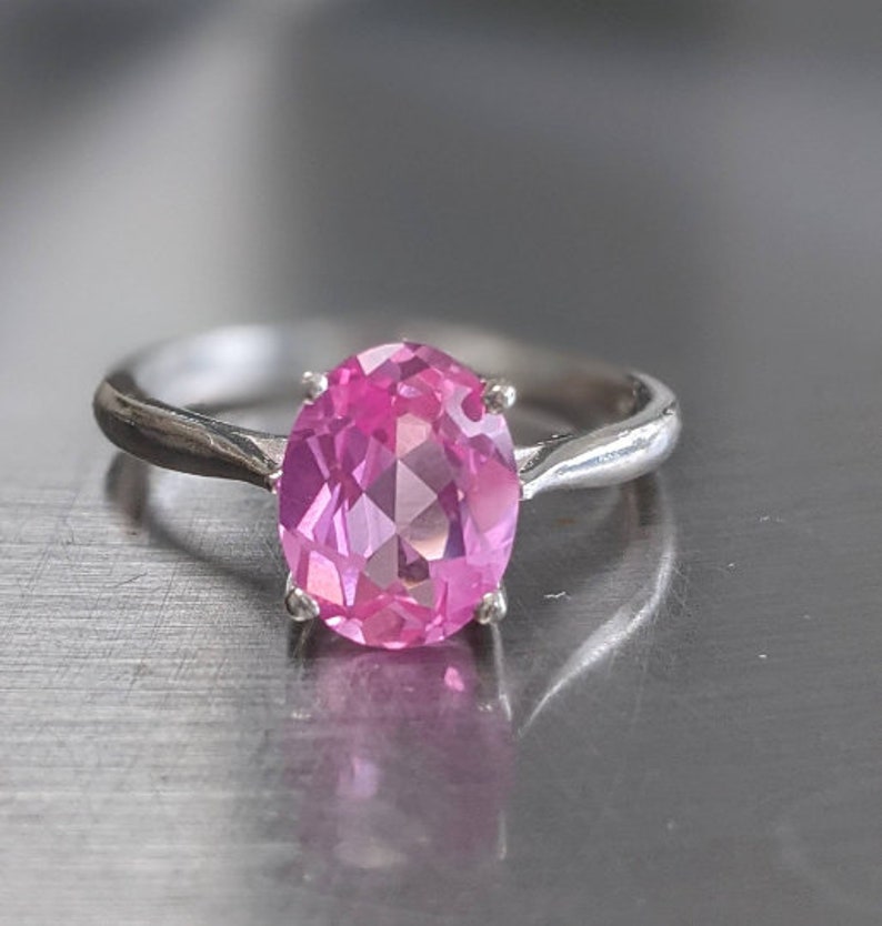 May include: A silver ring with a large oval pink gemstone.