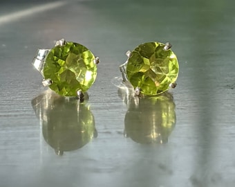 Könnte beinhalten: Ein Paar silberne Ohrringe mit runden grünen Peridot-Edelsteinen.