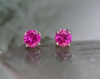 May include: A pair of silver stud earrings with pink gemstones.