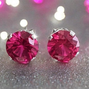 May include: A pair of silver stud earrings with bright pink round gemstones.