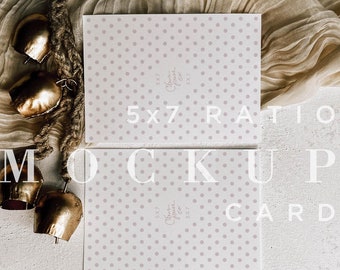 May include: Two white 5x7 inch cards with a light purple polka dot pattern. The cards are laying flat on a white textured surface with a tan fabric and gold bells in the background. The text "5x7 Ratio Mockup Card" is printed on the surface.
