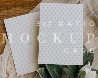 May include: Two white cards with a light purple polka dot pattern. The cards are laying on a light brown fabric with a wooden tray underneath. The text "5x7 RATIO MOCKUP CARD" is printed on the top card. The text "Citrus Press Co." is printed on both cards.