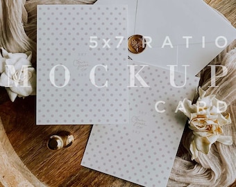 May include: A mockup card set with a white envelope, a card with a polka dot pattern, and a gold wax seal. The card set is on a wooden tray with fabric and flowers. The text "5x7 RATIO MOCKUP CARD" is overlaid on the image.