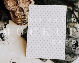 May include: A white card with a light purple polka dot pattern. The card is laying on a black fabric with a gold skull and black spiders. The text on the card reads "5x7 Ratio Mockup Card".