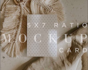 May include: A white card with a dotted pattern and the text "5x7 Ratio Mockup Card" on a light brown surface with a beige fabric and a macrame feather hanging above the card.