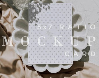 May include: A white card with a gray polka dot pattern and the text "5x7 Ratio Mockup Card" in white. The card is sitting on a white marble dish with a scalloped edge. The dish is on top of a beige fabric.