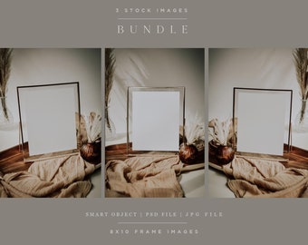 May include: Three 8x10 inch frames with white mats and a gold frame are displayed on a wooden surface with a tan fabric draped over the front. Dried pampas grass is in vases on either side of the frames.