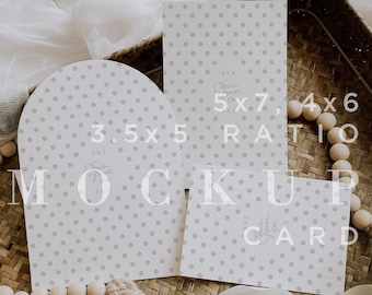 Può includere: Un set di biglietti mockup con un motivo a pois grigio chiaro. Il set include un biglietto ad arco da 3,5 x 5 pollici, un biglietto da 5 x 7 pollici e un biglietto da 4 x 6 pollici. I biglietti sono disposti su un cestino intrecciato con elementi decorativi.
