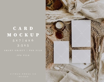 May include: Two blank white cards on a woven placemat with a candle, dried flowers, and a linen cloth. The cards are 5x7, 4x6, and 3.5x5 inches.  The text "CARD MOCKUP 5x7 | 4x6 3.5x5 SMART OBJECT | PSD FILE JPG FILE CITRUS PRESS CO IMAGES" is on a light gray background.