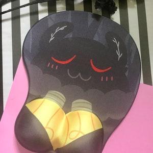 Pode incluir: Tapete de rato ergonómico com um design de desenho animado. A almofada apresenta um fundo cinza escuro com um rosto sorridente e duas lâmpadas amarelas. O apoio para o pulso é de cor castanho escuro.