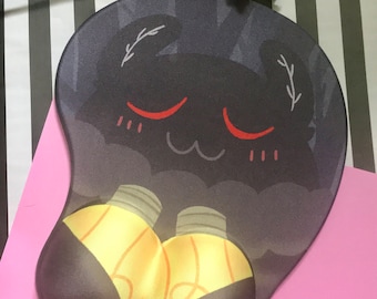 May include: Ergonomic mouse pad with a cartoon design. The pad features a dark gray background with a smiling face and two yellow light bulbs. The wrist rest is a dark brown color.