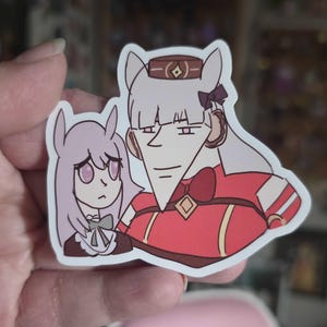 May include: A sticker featuring two anime-style characters. One character is in a red and brown outfit with a bow tie, and the other is in a purple dress. The sticker has a white border.