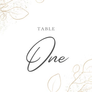 May include: A white table number card with gold leaf accents and the text "TABLE One" in black script.