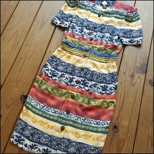 May include: A colorful striped dress with a floral pattern and button closures. The dress has a fitted bodice and a flowing skirt.