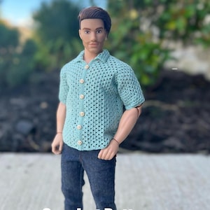 May include: A crochet pattern for a light blue button-up shirt with short sleeves. The shirt is made with a simple stitch and has a relaxed fit.