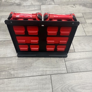 May include: A black metal tool organizer with red tool holders. The organizer has multiple slots for tools and a top section for larger items. The tools are red and the organizer is on a wooden floor.