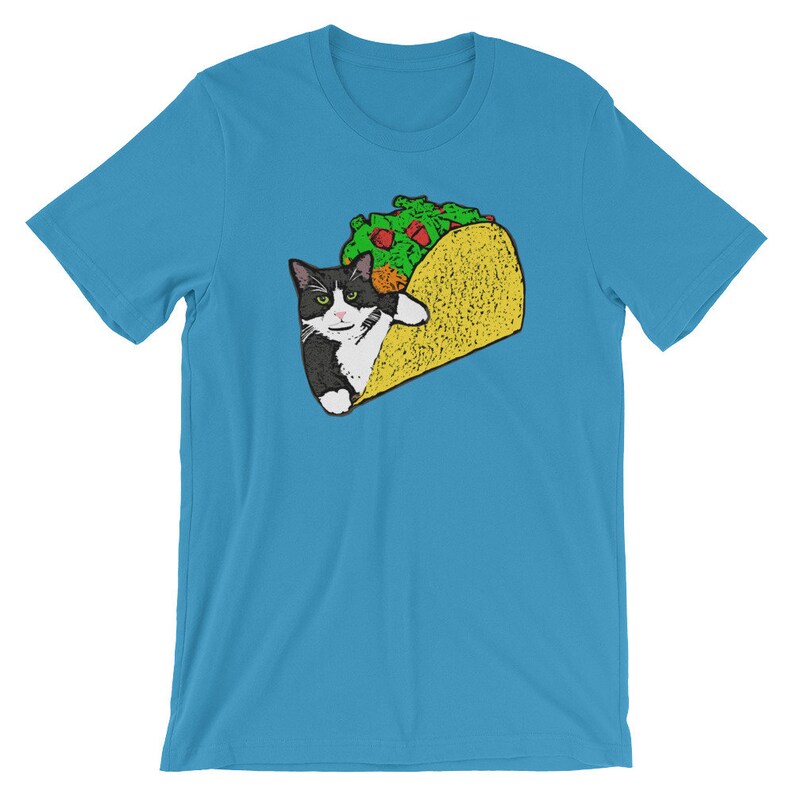 May include: A turquoise blue t-shirt with a black and white cat inside a yellow taco. The cat is looking at the viewer with a serious expression.