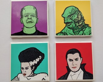 May include: Four square coasters featuring different classic monster characters. The coasters are white with a purple, yellow, blue, and red background. The characters are Frankenstein, Creature from the Black Lagoon, Bride of Frankenstein, and Dracula.