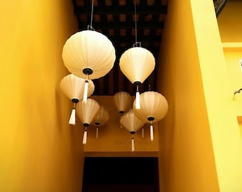 May include: A hallway with yellow walls and a ceiling with a wooden grid pattern.  Multiple white paper lanterns hang from the ceiling, with tassels.