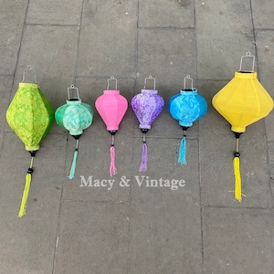 May include: Seven colorful silk lanterns with tassels hanging from the ceiling. The lanterns are in shades of green, pink, purple, and blue.