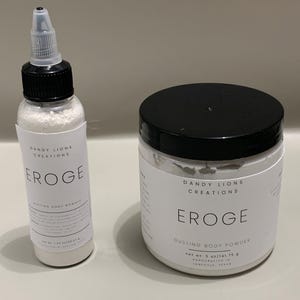 May include: A Dandy Lions Creations EROGE dusting body powder set featuring a tall squeeze bottle with a black cap and a wide jar with a black lid. The bottle label states net wt 1.5 oz and the jar label states net wt 5 oz/141.75 g.