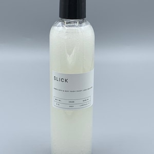 May include: A clear plastic bottle with a black cap, filled with a white, bubbly liquid. The label reads "SLICK Bubble Bath & Body Wash." The bottle contains 8 oz of product.