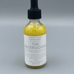 May include: A clear glass bottle of bath and body oil with a black dropper. The oil inside is yellow and has the text "THE BACKROOMS" on the label. The label also says "DANDY LIONS CREATIONS" and "net wt. 1.7 fl oz (50 ml)."