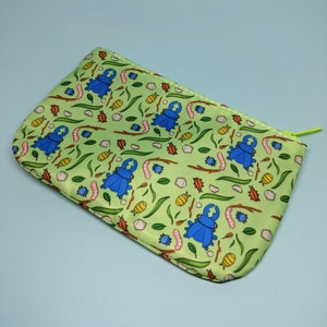 May include: A green zippered pouch with a repeating pattern of blue beetles, brown twigs, and yellow and white flowers.