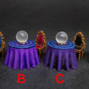 May include: Four miniature tables with purple and green tablecloths, each with a crystal ball on top. The tables are set with chairs in various colors, including gold, red, and green.