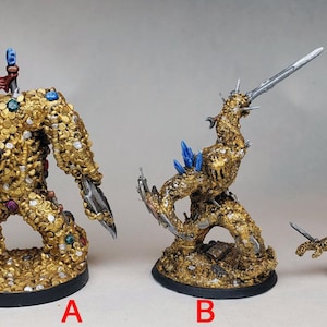 May include: Three gold-painted miniature figures, each with a different pose and design. The largest figure is a humanoid with a red gem on its chest, holding a sword. The middle figure is a dragon-like creature with blue gems on its back, holding a sword. The smallest figure is a small, crouching creature with a sword.