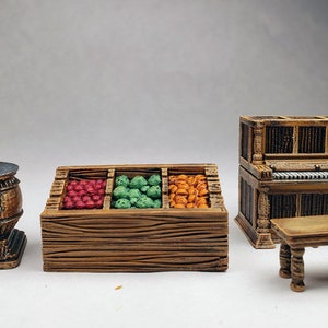 Könnte beinhalten: Ein Set aus vier Miniaturmöbeln aus Holz, darunter ein Holzofen, ein Obststand mit drei Fächern gefüllt mit roten, grünen und orangen Früchten, ein kleiner Tisch und ein Miniaturklavier.