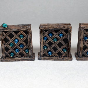 Könnte beinhalten: Vier Holz-Weinständer mit einem Rautenmuster, die jeweils mit blauen Glasflaschen gefüllt sind. Zwei der Ständer haben ein kleines Holzfass daneben.