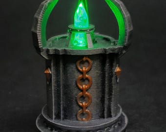 May include: A black and green 3D printed miniature of a glowing crystal on a pedestal with a chain design.