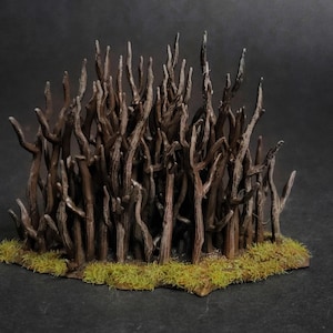 May include: A miniature terrain piece, hand-painted to depict a cluster of stylized, dark brown, leafless trees. The trees are set on a base with patches of green moss, creating a forest scene. The background is a dark grey.