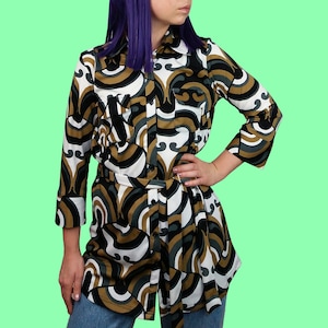 Può includere: Camicia abbottonata con motivo retrò in nero, bianco, verde oliva e beige, con cintura abbinata. La camicia ha maniche a tre quarti e viene indossata con jeans blu.
