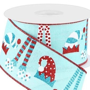 May include: A spool of light blue Christmas ribbon with a repeating pattern of red and white holiday-themed designs. The ribbon features glitter accents and a red border. The spool is white.