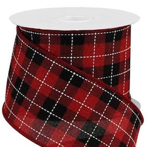 May include: A roll of decorative ribbon featuring a classic red and black plaid pattern. The ribbon has a white dotted grid overlaying the plaid design. The spool is white.