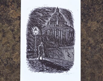May include: A black and white linocut print on white paper depicting a person in a coat walking past a street lamp and a domed building at night. The scene features heavy rain, a metal fence, and a signature in the bottom right corner.