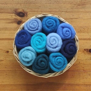 May include: A basket filled with ten blue and teal felt balls, arranged in a circular pattern.