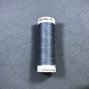 Könnte beinhalten: Eine Spule Gütermann-Garn in dunkelblau. Die Spule ist mit "Gütermann" und "220 yds/vgs" beschriftet.