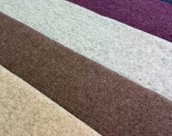 May include: A collection of five rectangular felt fabric swatches arranged in a diagonal stack. The colors include dark navy blue, deep purple, light heather gray, medium brown, and a soft beige, all featuring a consistent textured finish.