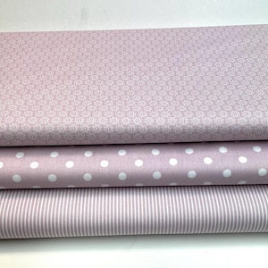 Könnte beinhalten: Drei Stoffstücke in Rosatönen. Das obere Stück hat ein weißes Blumenmuster, das mittlere Stück hat weiße Punkte und das untere Stück hat weiße Streifen.