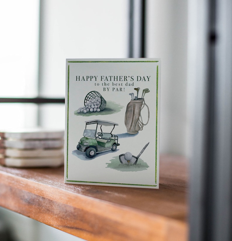 May include: A green and white Father's Day card with the text "Happy Father's Day to the best dad by par!" and illustrations of golf equipment, including a golf cart, golf clubs, and golf balls.