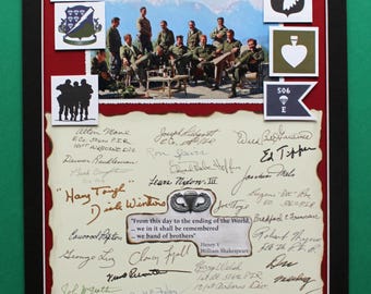May include: Framed military memorabilia featuring a photograph of soldiers, various unit patches, and handwritten signatures. The image includes the word "AIRBORNE" and a quote from Shakespeare. The frame is black with a red mat.