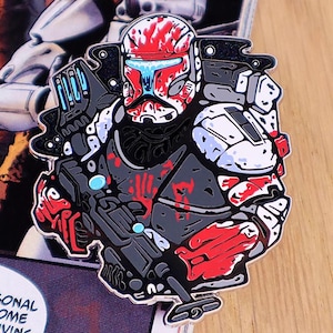 Puede incluir: Pin de esmalte detallado que representa a un soldado estilizado con casco y armadura. El pin tiene un esquema de color rojo, negro, gris y blanco. El casco del soldado es rojo con detalles blancos y azules. Probablemente un artículo de colección.