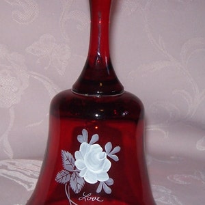 Puede incluir: Una campana de vidrio roja pintada a mano con un diseño de rosa blanca y hojas. La campana tiene la palabra "Love" escrita en ella.