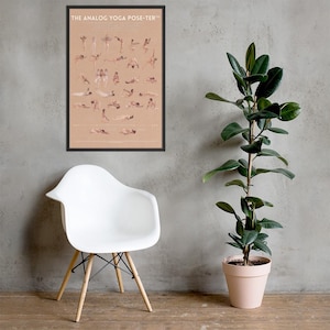 May include: A framed poster titled "THE ANALOG YOGA POSE-TER" displays various yoga poses in a minimalist style. The poster is set against a neutral wall, with a white chair and a potted plant in the foreground. The poster is in a black frame.