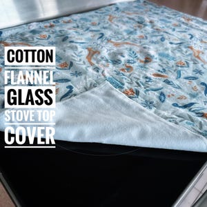May include: A cotton flannel glass stove top cover with a light blue background and a repeating pattern of orange foxes, blue birds, and floral elements. The text "COTTON FLANNEL GLASS STOVE TOP COVER" is printed in white.